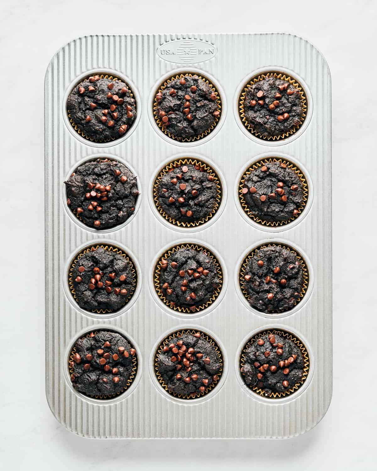 A muffin tin full of baked vegan chocolate sweet potato muffins.