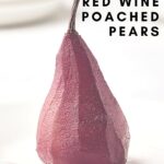 pin and side view of red wine poached pear on white plate with white background