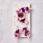 Top down view of vegan blueberry coconut popsicles on white plate.