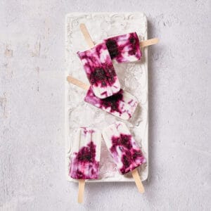Top down view of vegan blueberry coconut popsicles on white plate.