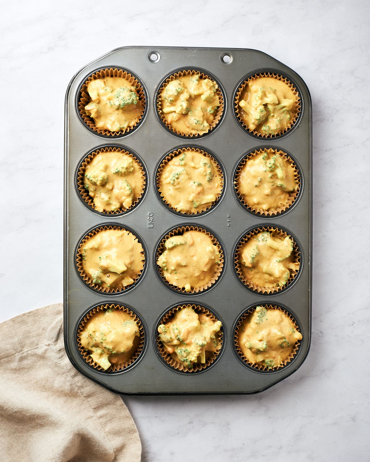 Top down view of broccoli cheddar egg cups batter in muffin tin