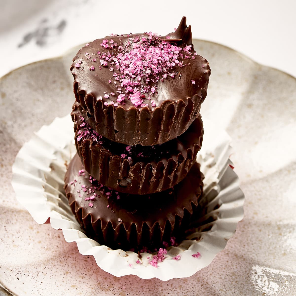 Side view of stack of chocolate peanut butter cups with salt on top