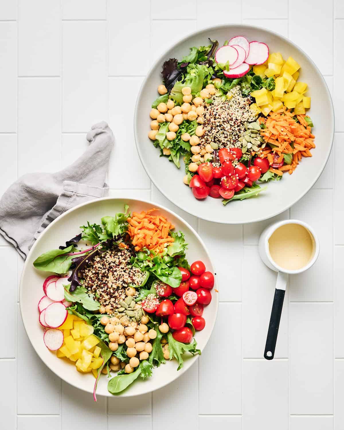 Two bowls of Quinoa Chickpea Salad with dressing on the side.