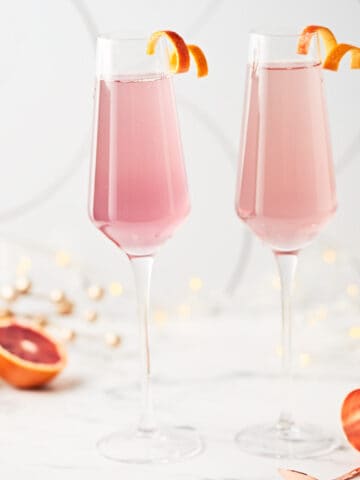 side view of 2 glasses filled with blood orange french 75