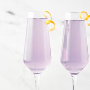 Side view of 2 glasses of Meyer Lemon French 75 with citrus twists