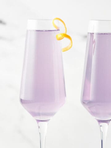 Side view of 2 glasses of Meyer Lemon French 75 with citrus twists