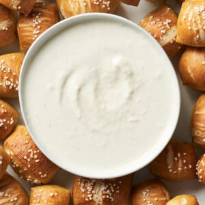 Top view of Horseradish Aioli in white bowl surrounded by pretzel bites