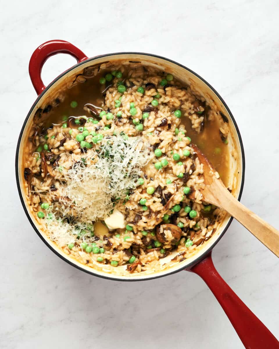 Mushroom risotto with peas and all ingredients in saucier on marble background