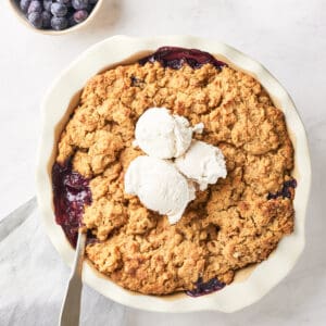 baked vegan blueberry cobbler in pie dish with scoops of dairy free ice cream