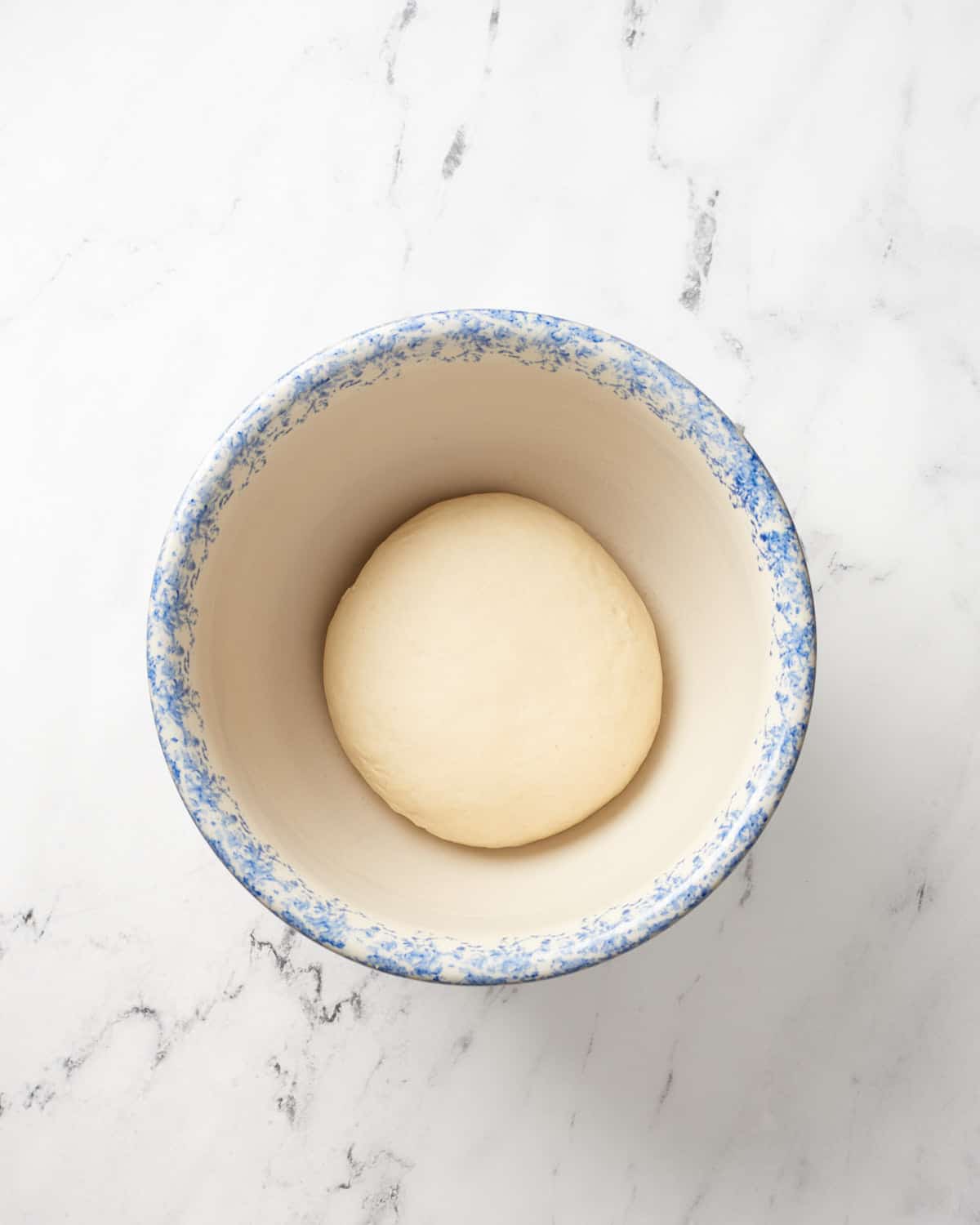 Pretzel dough ball in large bowl on marble background