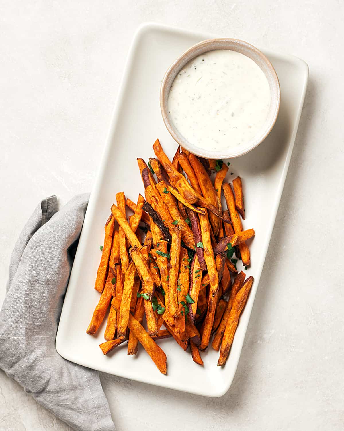 Crispy baked sweet potato fries on white tray with vegan ranch dip