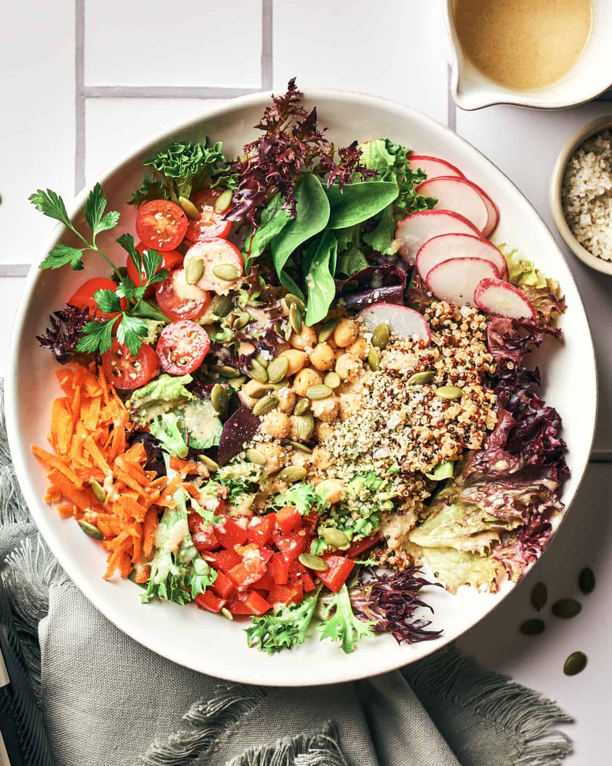 white bowl of vegan chickpea quinoa salad on subway tile background with grey napkin