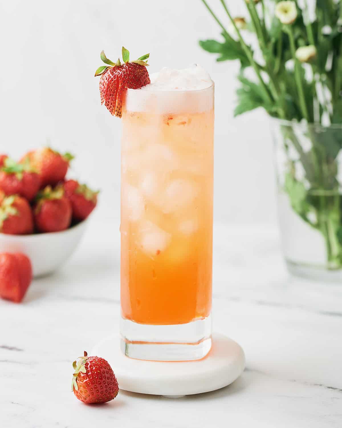 Glass of Strawberry Elderflower Gin Fizz in tall glass with strawberry garnish.