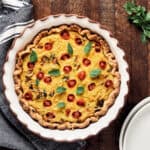 Overhead view of quiche in pie dish on wood surface.