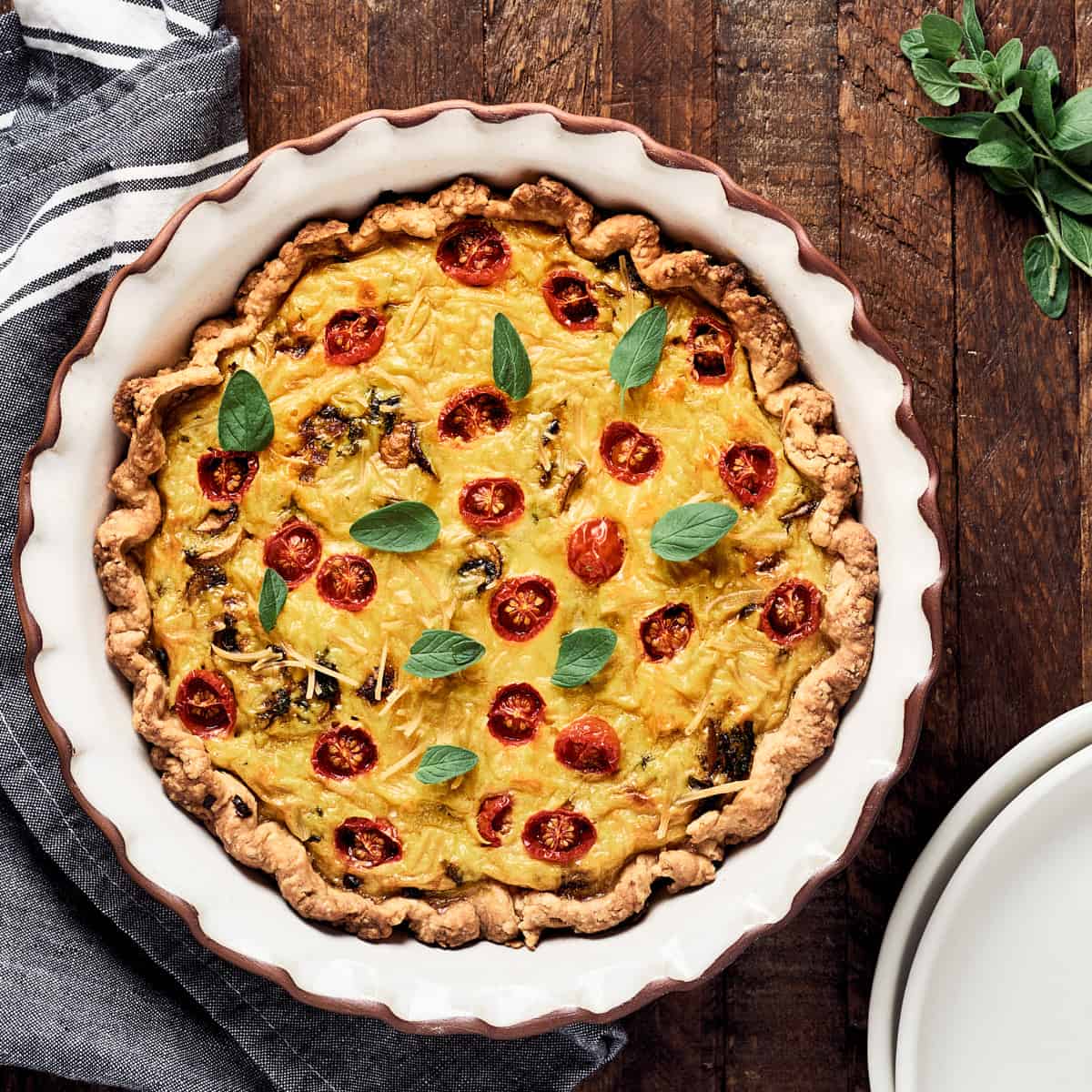 Overhead view of quiche in pie dish on wood surface.