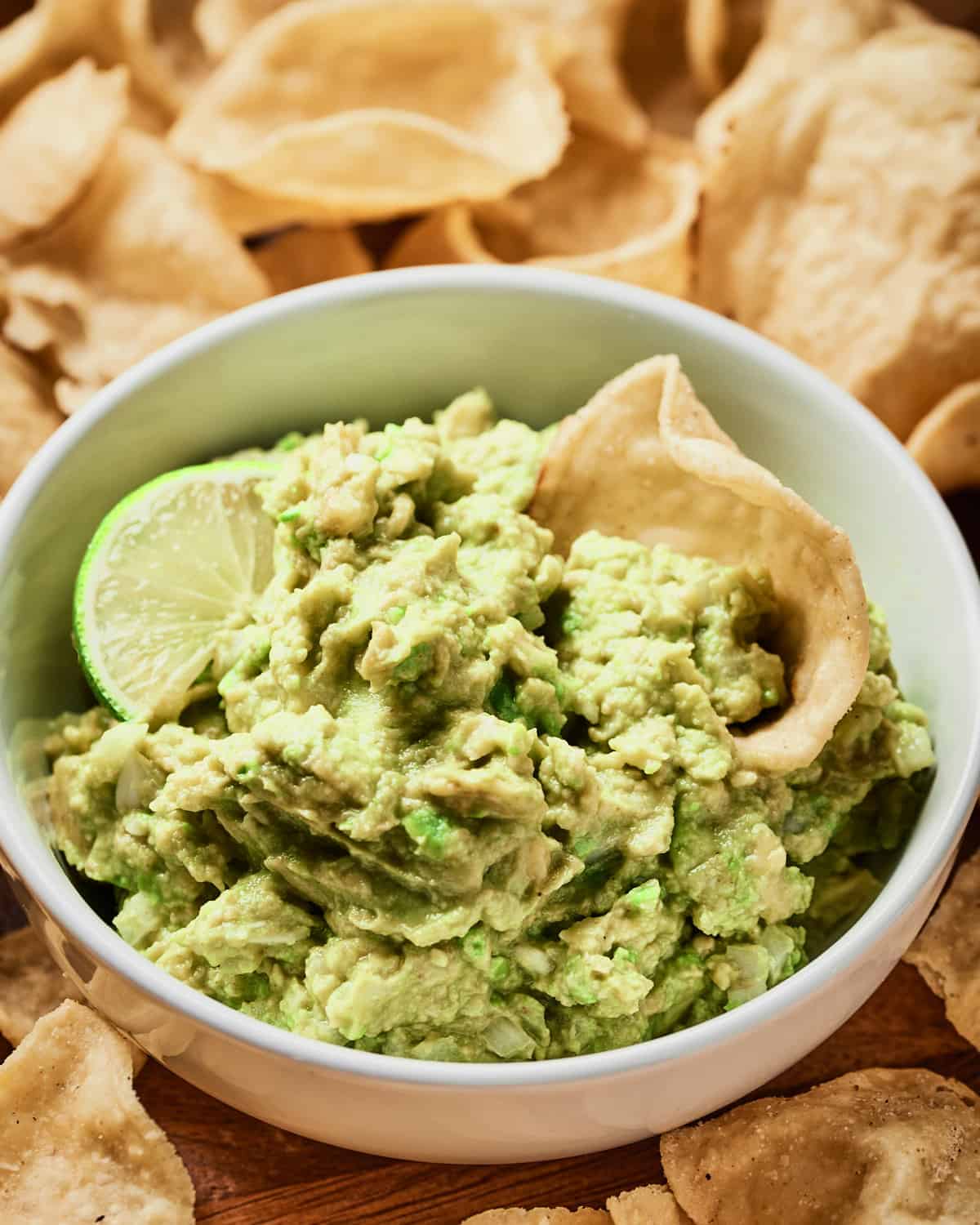 Top down view of 4 ingredient guacamole in white bowl with tortilla chips