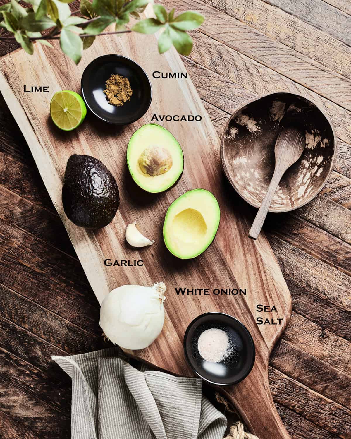 Top down view of guacamole ingredients on wooden table.