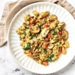 Top view of vegan mushroom vegan egg scramble on white plate with beige napkin.