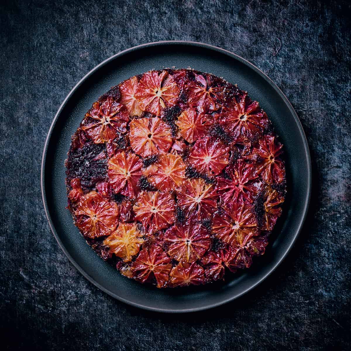 Top view of Vegan Chocolate Blood Orange Cake on dark blue background.