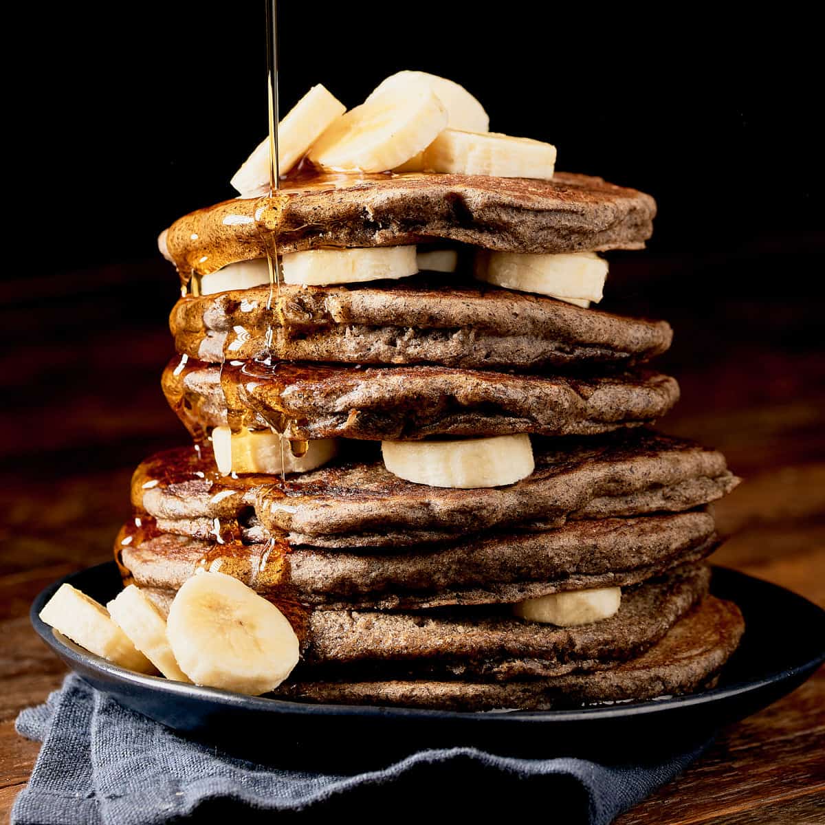 Side view of stack of buckwheat sourdough pancakes with bananas.