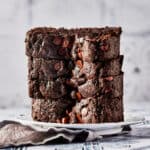 Side view of vegan chocolate tahini bread on a white plate with grey napkin.