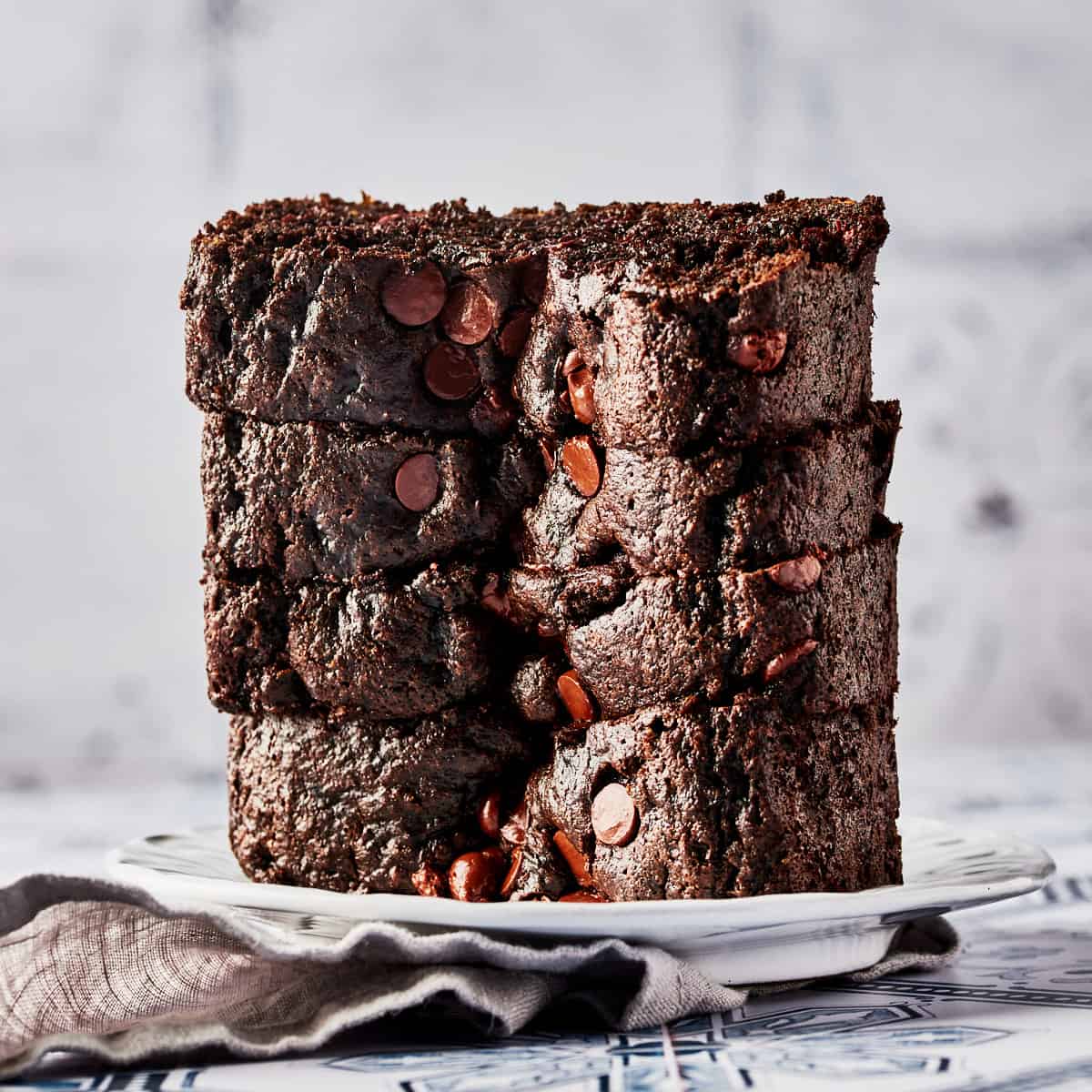Side view of vegan chocolate tahini bread on a white plate with grey napkin.