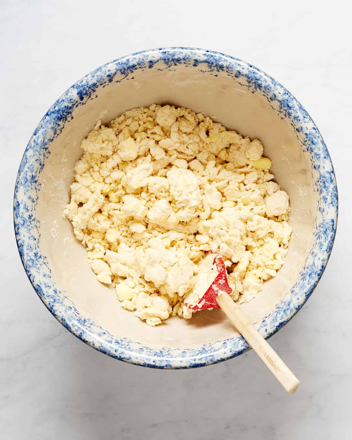 Overhead view of butter and shortening mixed with flour, water and vodka in a bowl.