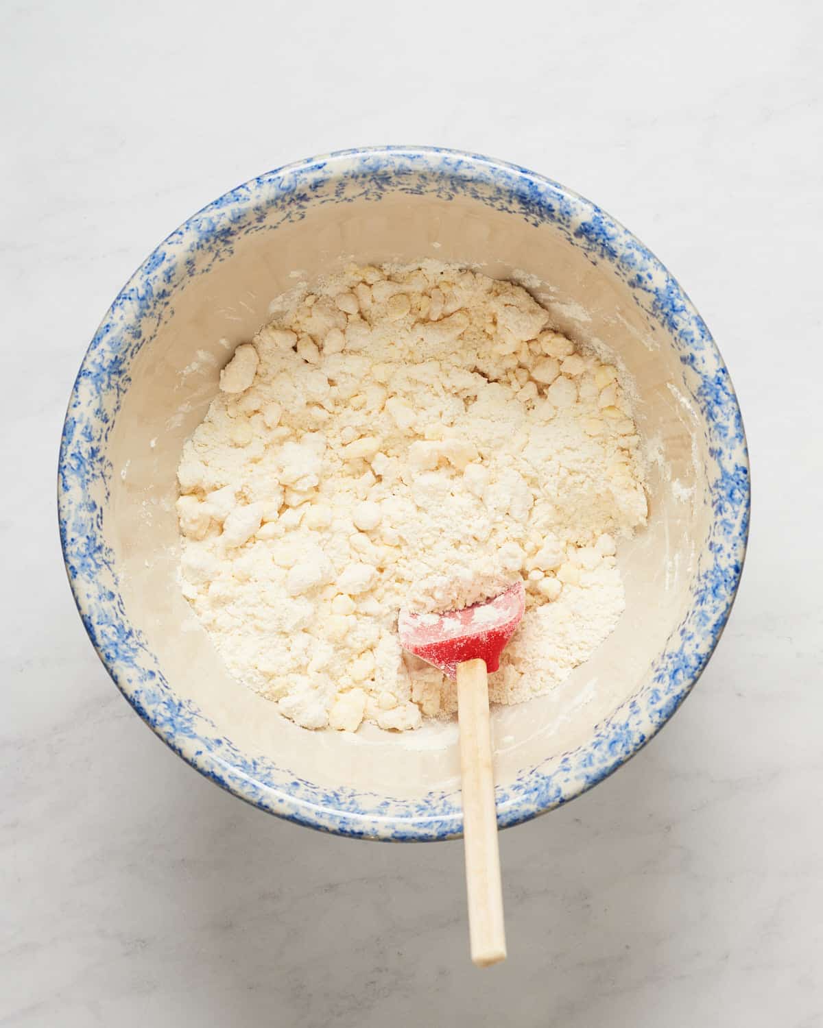 Overhead view of butter and shortening mixed with flour in a bowl.