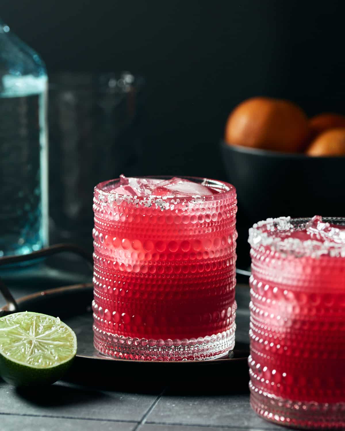 Side view of two glasses of blood orange pomegranate margarita.