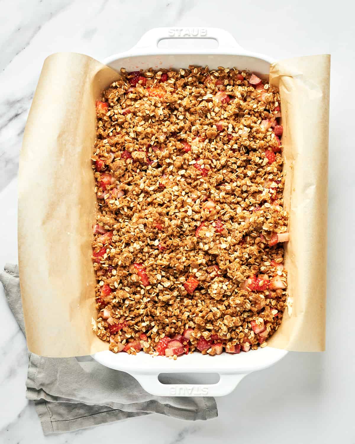 Overhead view of unbaked vegan strawberry rhubarb crumble bars in a rectangular baking dish.