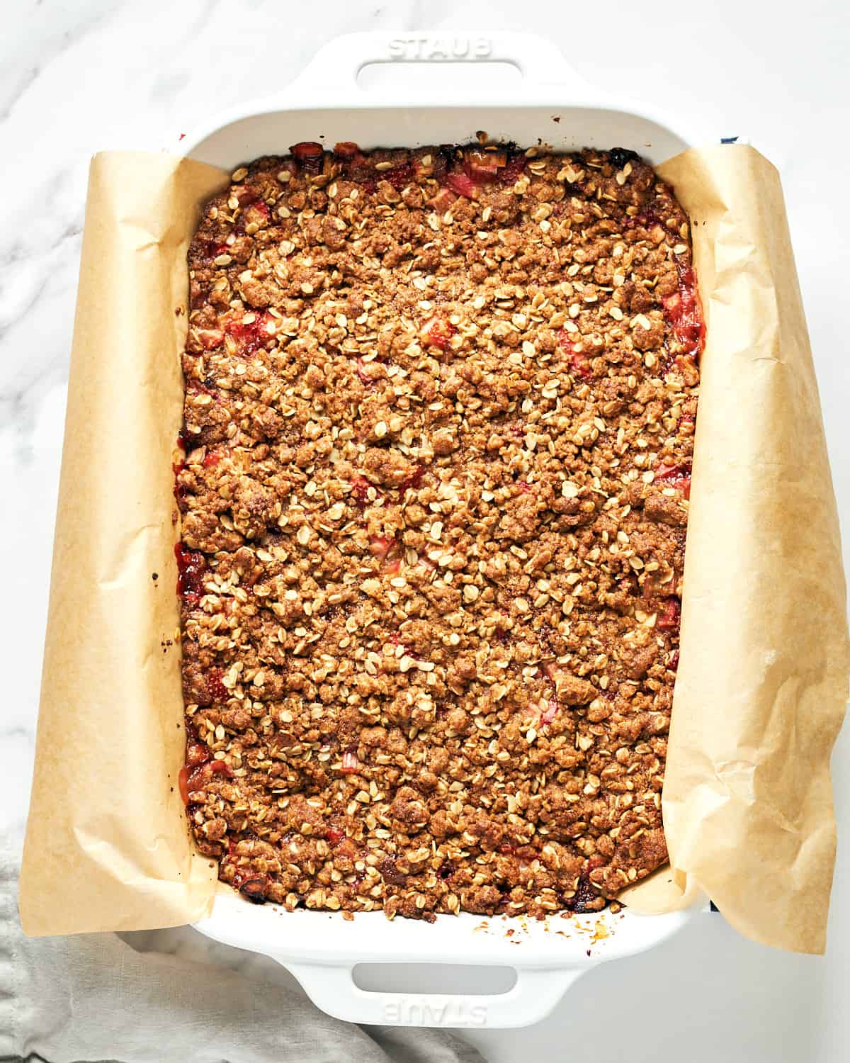 Overhead view of baked Vegan Strawberry Rhubarb Crumble Bars on a marble surface.
