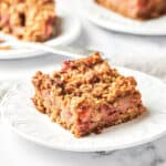 Side view of Vegan Strawberry Rhubarb Crumble Bars on white plates.