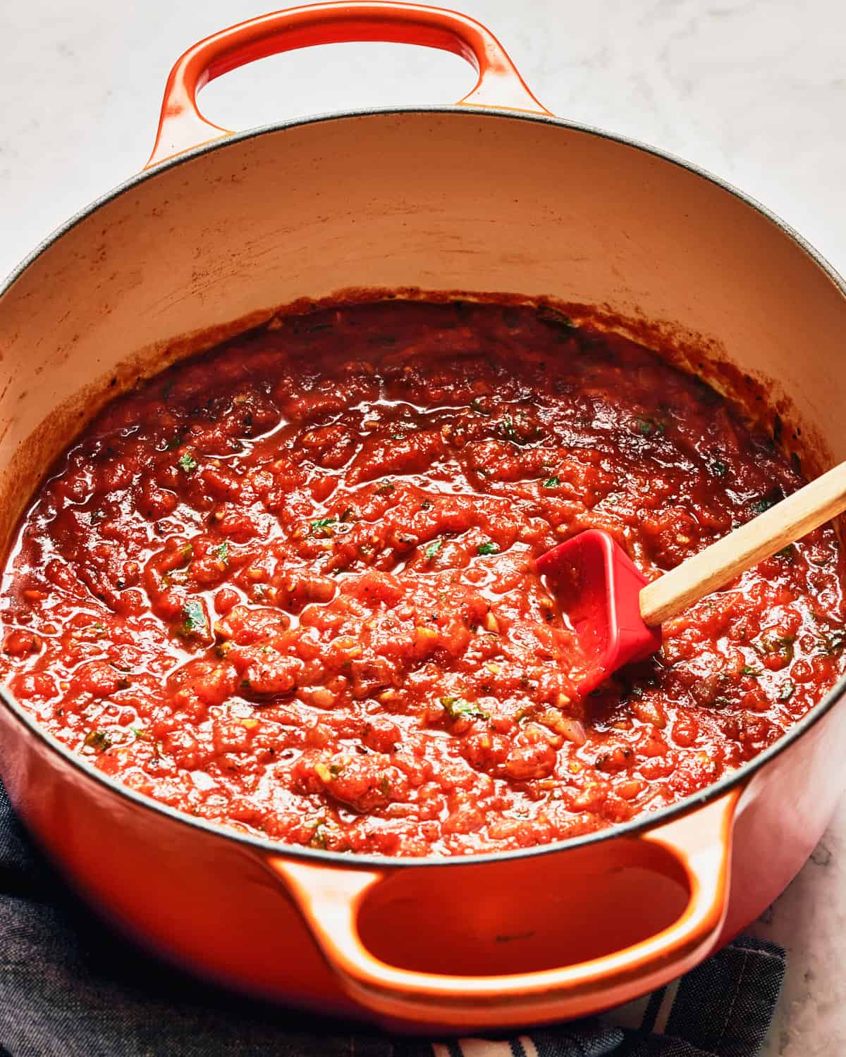 Overhead view of easy vegan marinara sauce in a large pot on a marble surface.