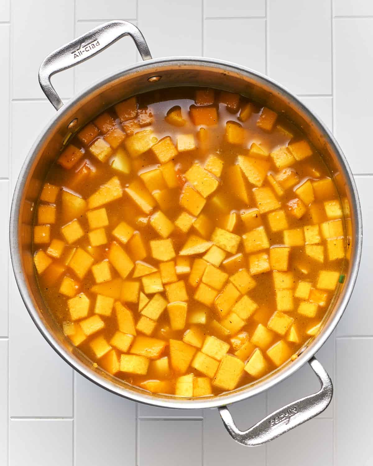 Overhead view of cooking vegan butternut squash curry soup in a large pot.
