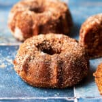 Side angle of vegan apple cider mini bundt cakes on blue tile surface.
