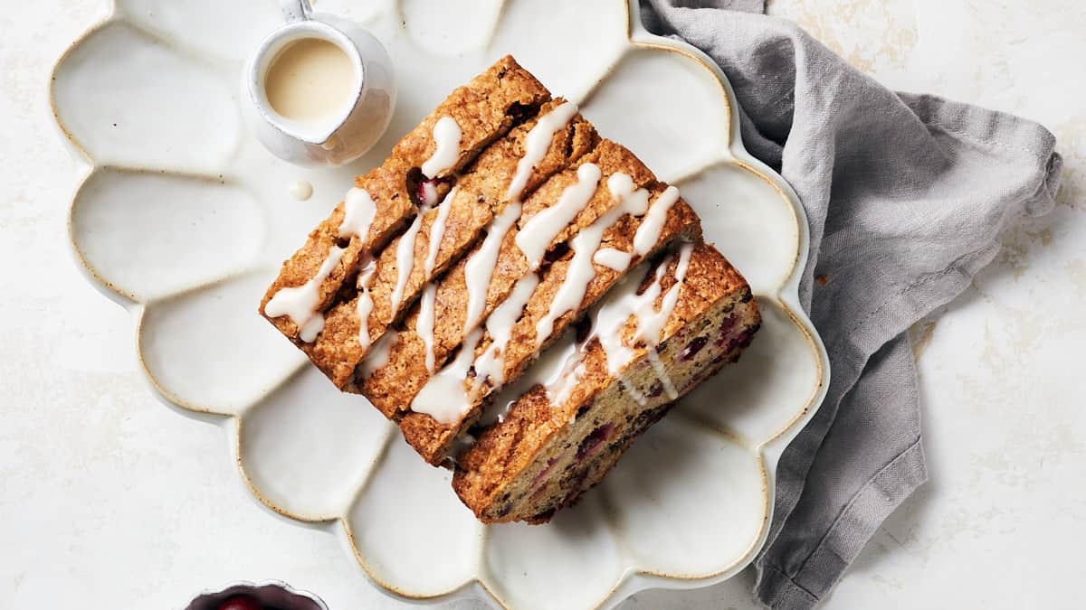 Overhead view of sliced vegan cranberry orange bread with icing drizzled on top.
