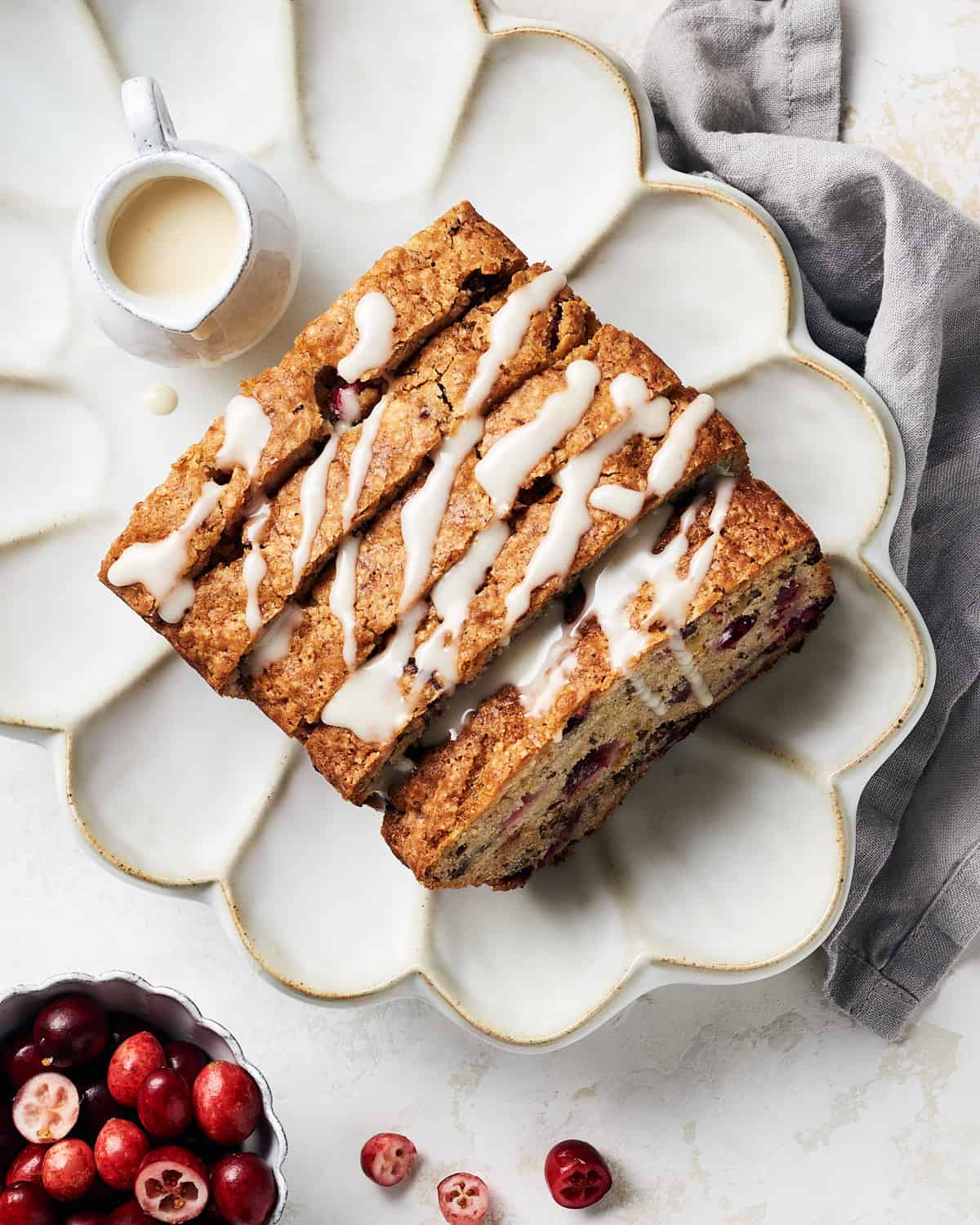 Overhead view of sliced vegan cranberry orange bread with icing drizzled on top.