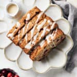 Overhead view of sliced vegan cranberry orange bread with icing drizzled on top.