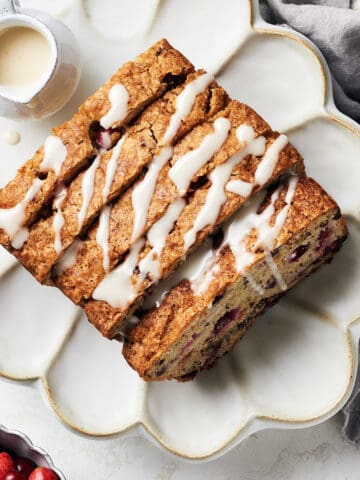 Overhead view of sliced vegan cranberry orange bread with icing drizzled on top.
