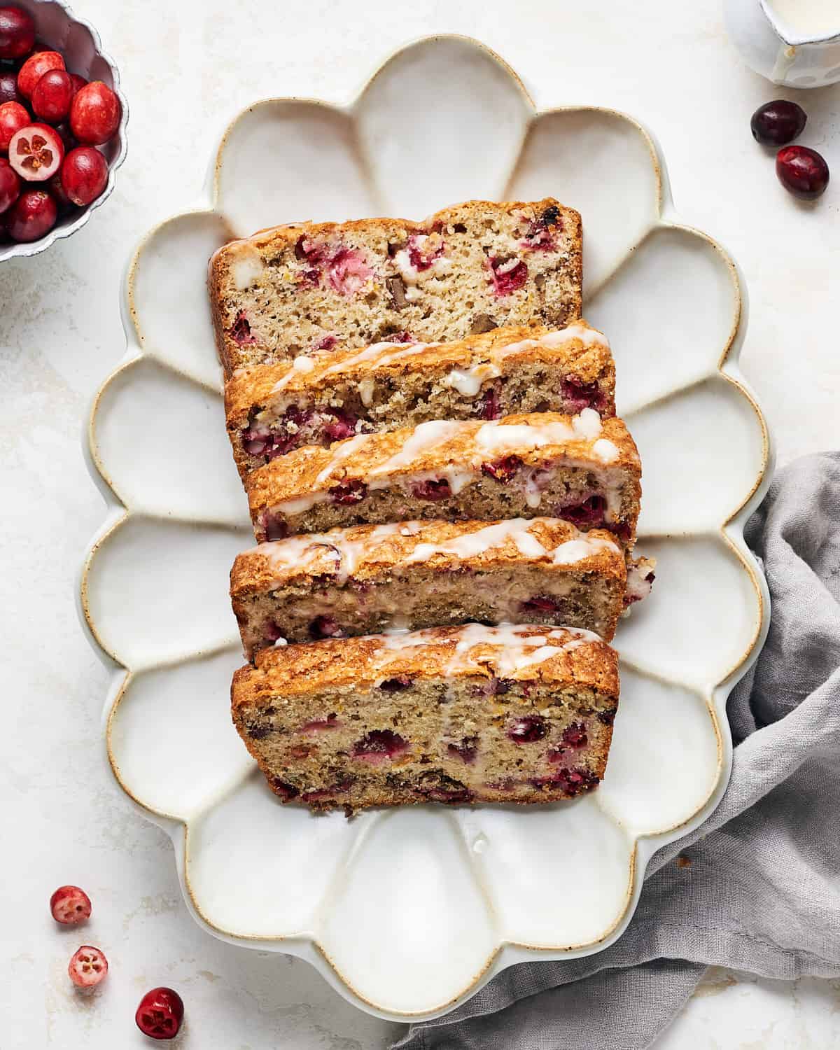 Overhead view of sliced vegan cranberry orange bread with icing drizzled on top.