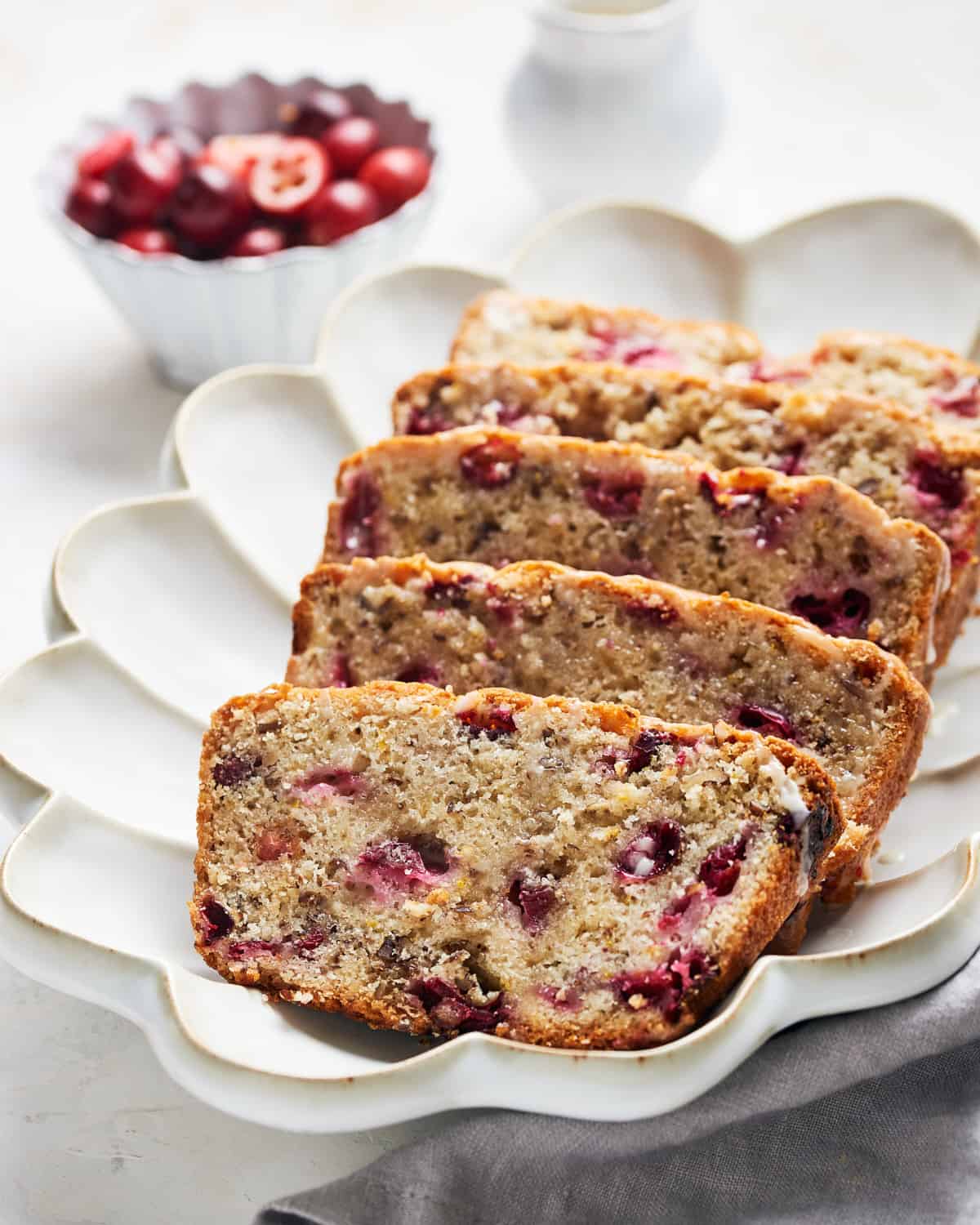 Side angle of several slices of vegan cranberry orange bread on a platter.