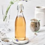 Side view of Homemade Lavender Simple Syrup for Cocktails on a marble background.