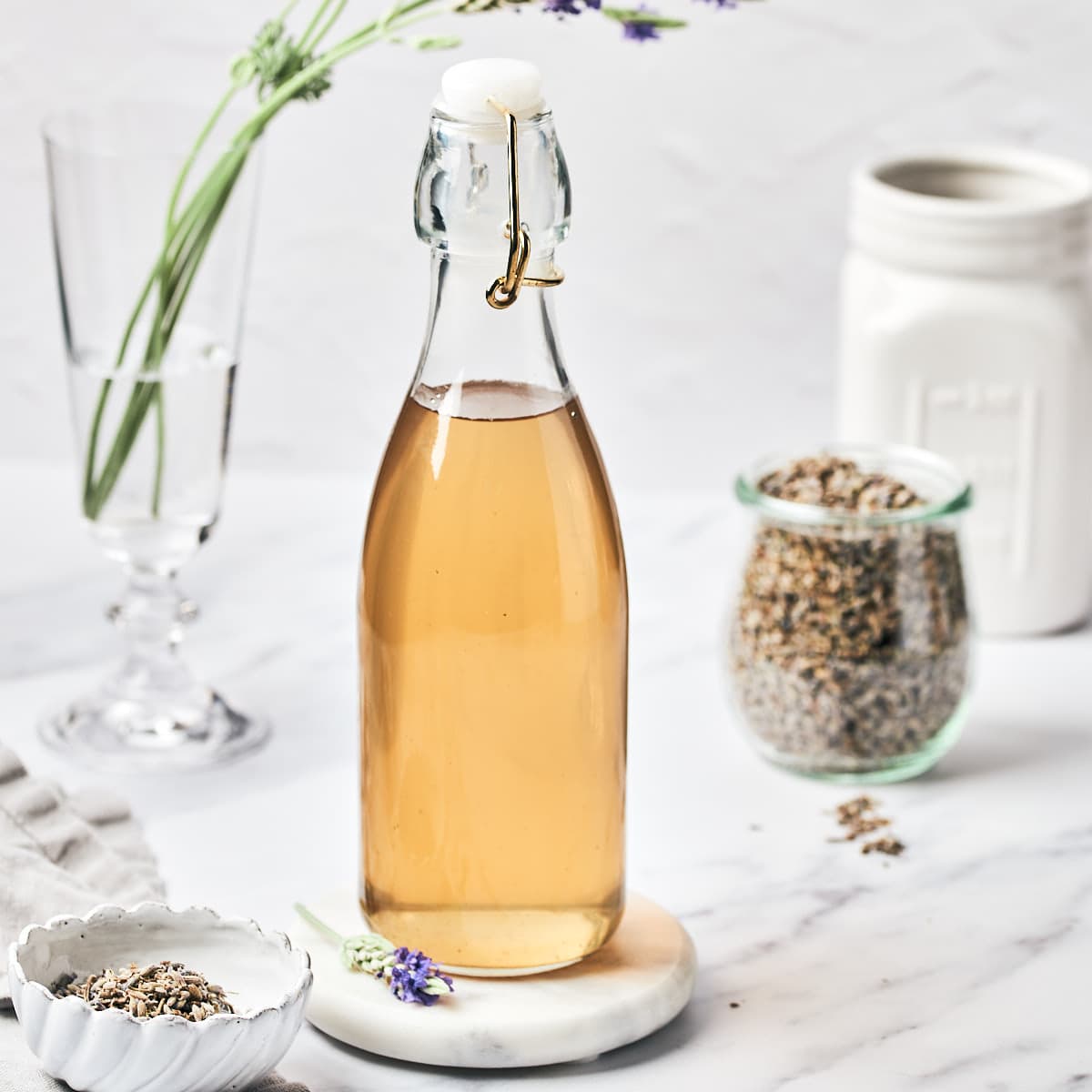 Side view of Homemade Lavender Simple Syrup for Cocktails on a marble background.