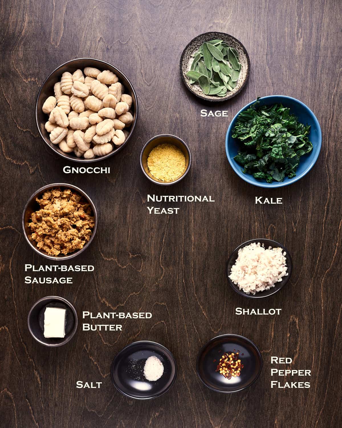 Overhead view of ingredients to make Gnocchi with Vegan Sausage and Browned Butter Sage on a dark wood background.