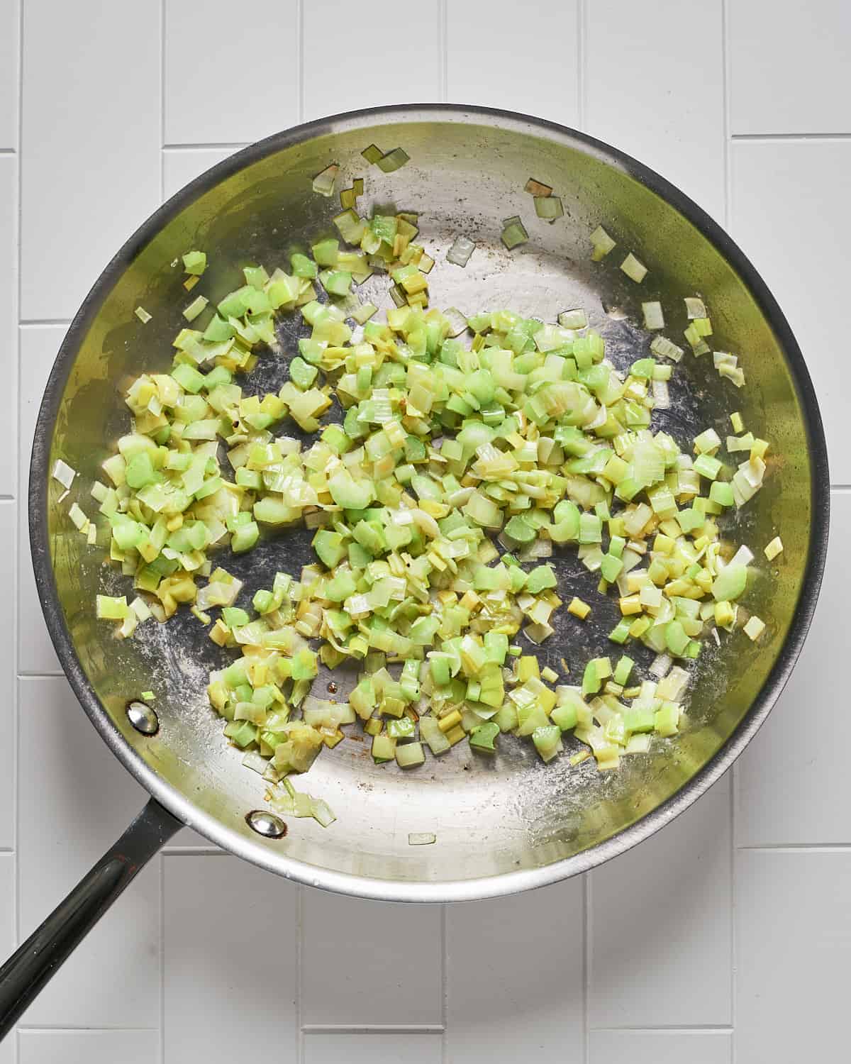 Overhead view of cooked chopped leeks in large skillet.