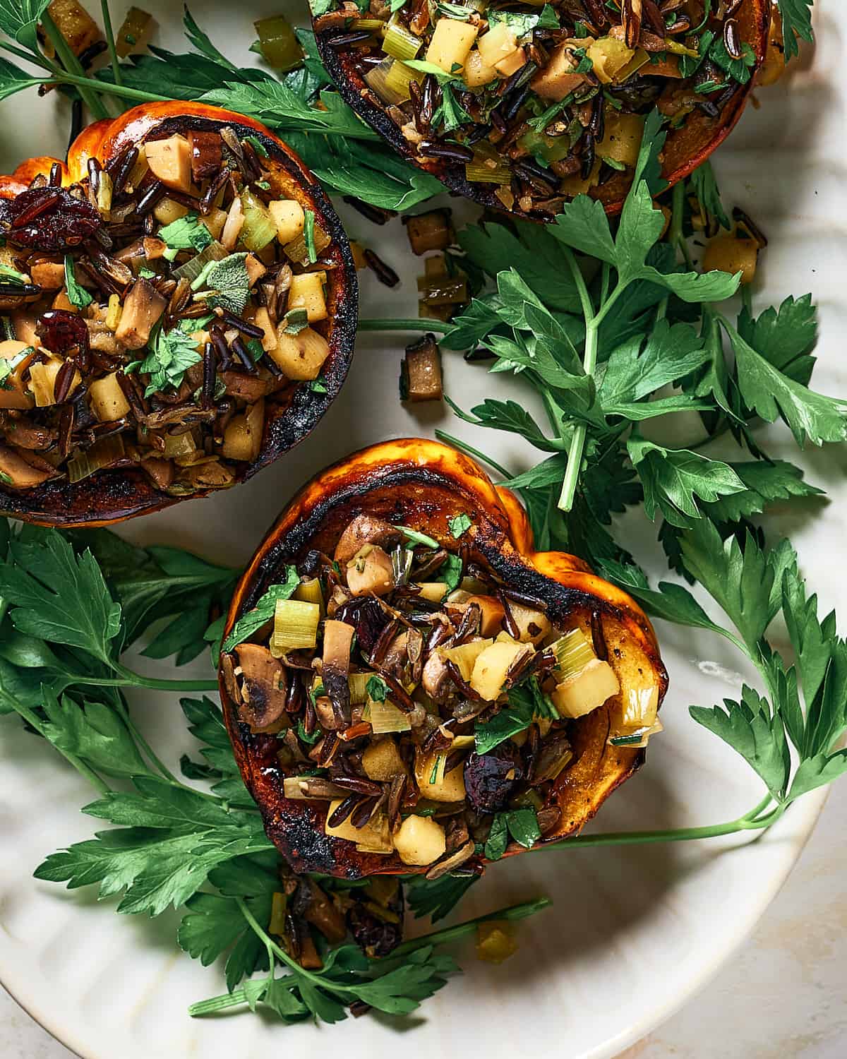 Overhead view of Roasted Stuffed Carnival Squash on a platter with fresh parsley.