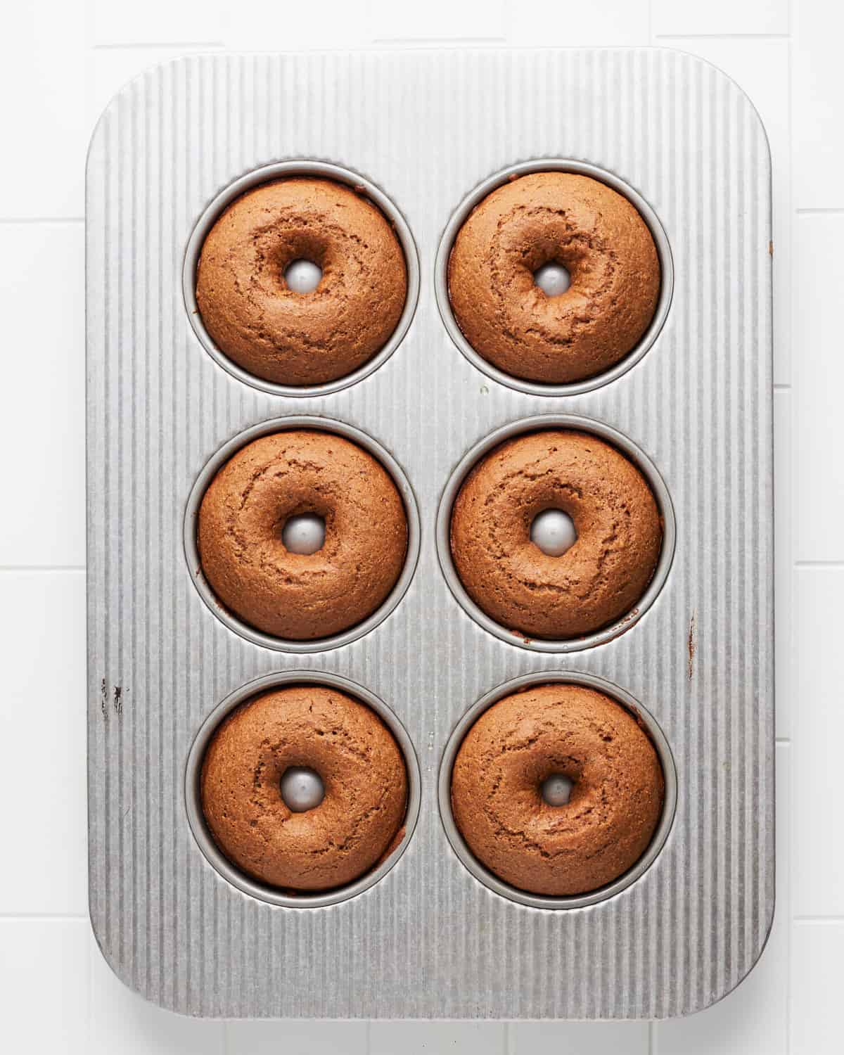 Overhead view of baked vegan apple cider donuts in baking pan.