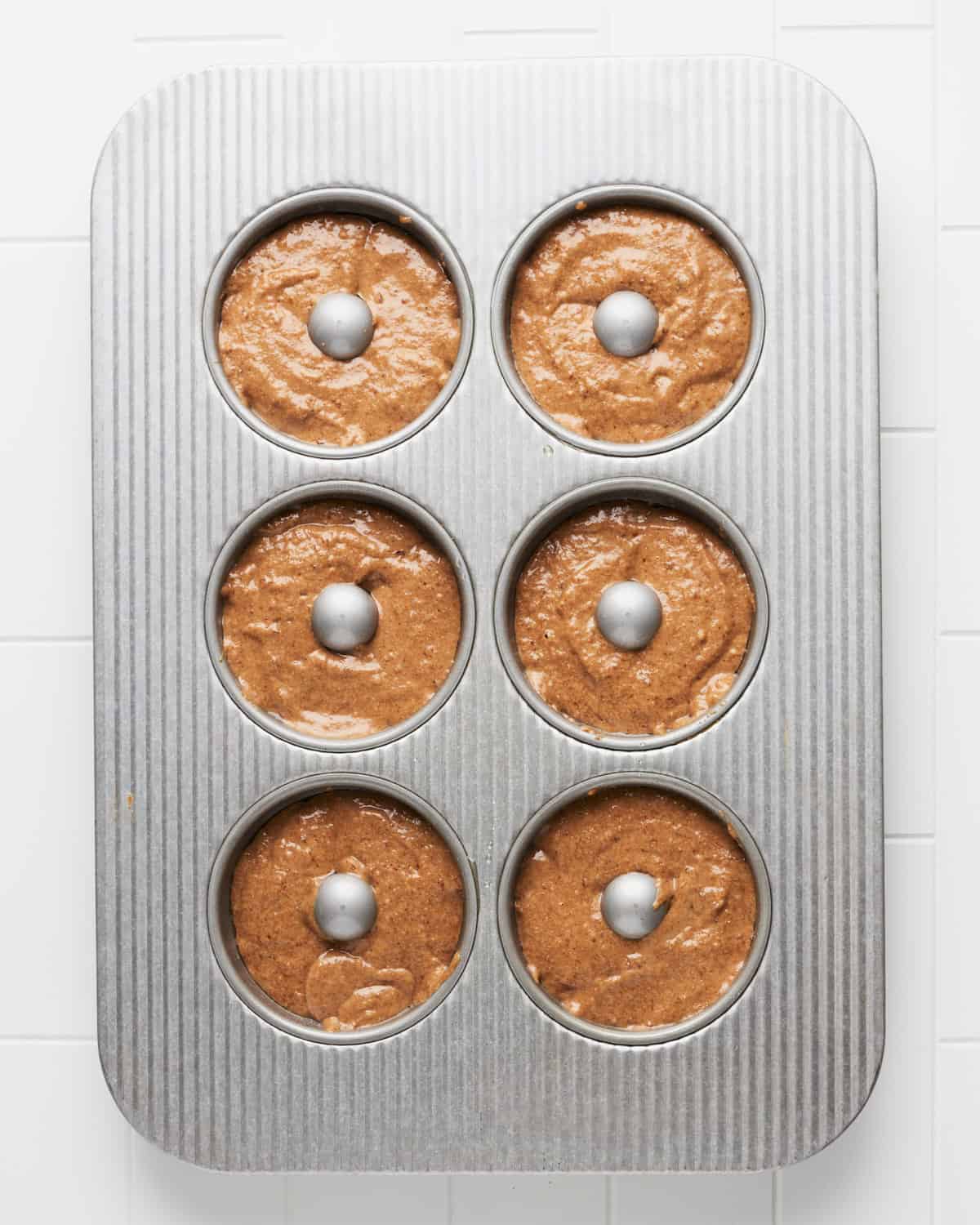 Overhead view of vegan apple cider donut batter in donut baking pan.