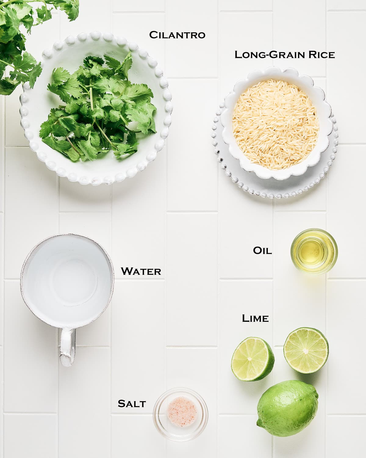Overhead view of Ingredients to make Cilantro Lime Rice in a Rice Cooker on a white tile background.