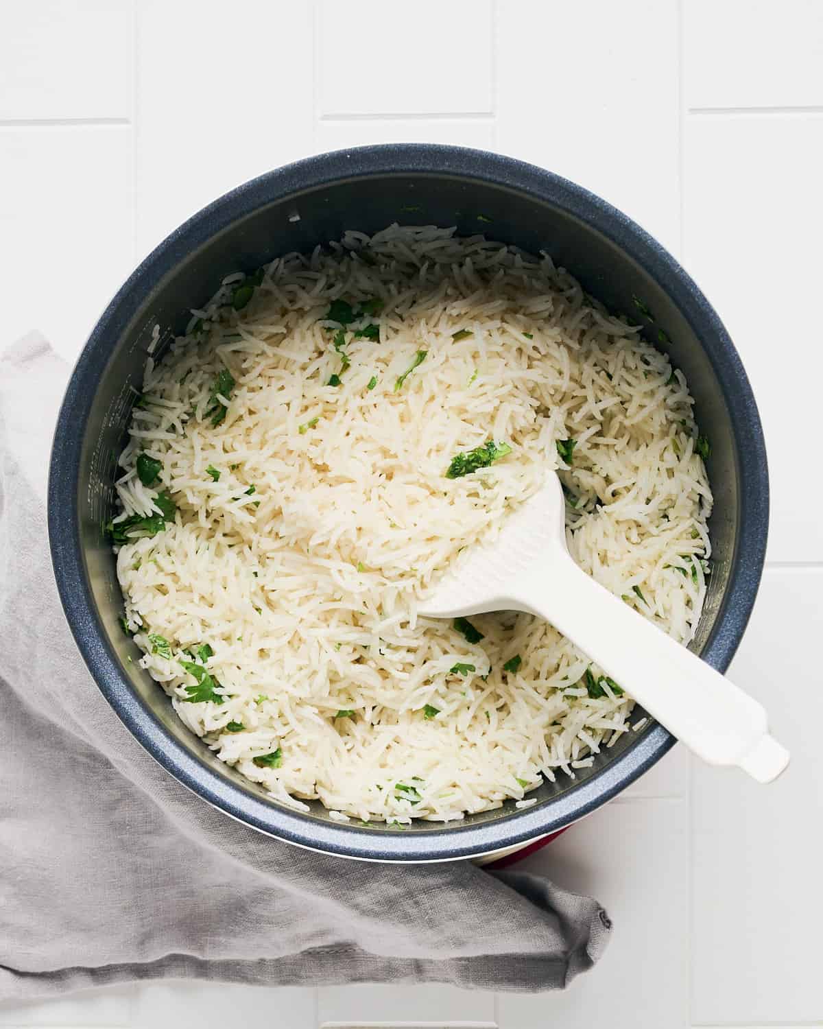 Overhead view of cooked long grain white rice mixed with cilantro, lime zest, and lime juice.
